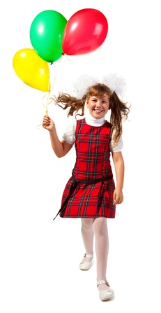 Happy school girl goes on a white background with colorful balloons in his hand の写真素材