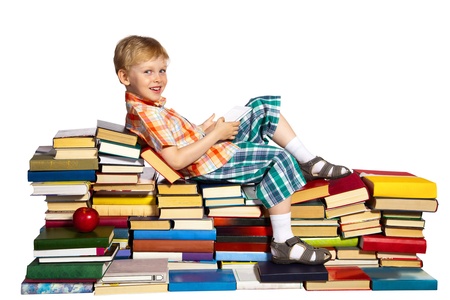 Little boy on a pile of books holds a tablet computer in his hands.の写真素材