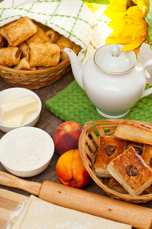 Appetizing pies from flaky pastry are on the wooden table, submitted with a fresh fruits, jam of peaches and tasty tea for breakfast の写真素材
