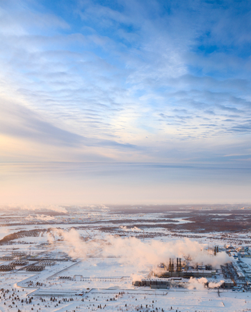 Aerial view of the oil refinery with smoking chimneys in winter against sunset. Fog is lying over the frozen tundra.の写真素材