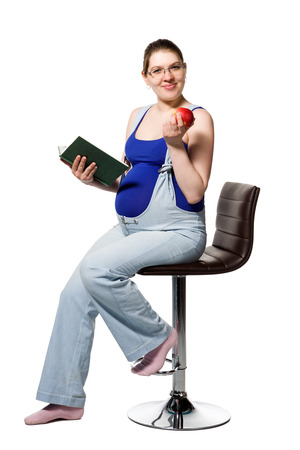 A pregnant young woman reading a book about pregnancy. Isolated on white background.の写真素材