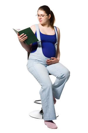 A pregnant young woman reading a book about pregnancy.の写真素材