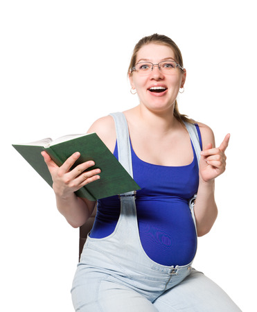 A pregnant young woman reading a book about pregnancy.の写真素材