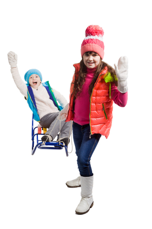 Little girls enjoying a sleigh ride. Child sledding. Sisters riding a sledge. Children play in snow. Outdoor winter fun for family Christmas vacation.の写真素材