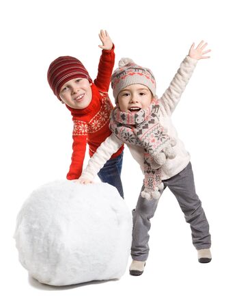 Funny adorable little children with comical big head making a snowman together, isolated on whiteの写真素材