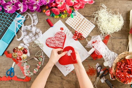 Materials and tools for hand decoration for Valentine's Day on a sacking. Female hands making red heart. Love and valentine concept.の写真素材