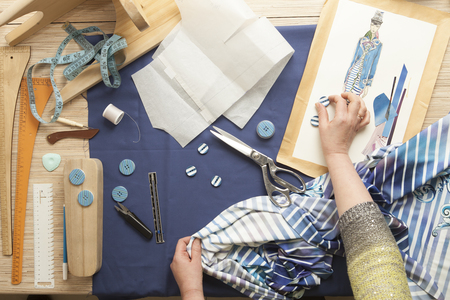 Desk designer fashion. Fashion designer starts cutting fabric to create fashionable clothes on the sketches.の写真素材