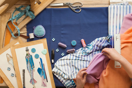 Desk designer fashion. Fashion designer starts cutting fabric to create fashionable clothes on the...