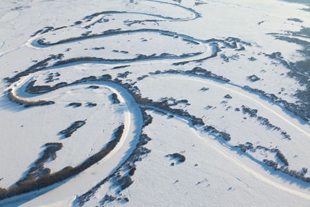 The Aerial view the intricately winding river on snow-covered plain in time of sunny winter day.の写真素材