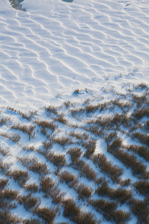 Sandy dunes covered snow on the river bankの写真素材