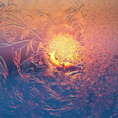 Frosty patterns on the window pane at sunset. Focus are in center.の写真素材