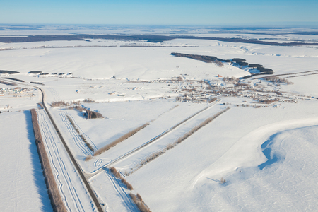 aerial view over snowy field and roadの写真素材
