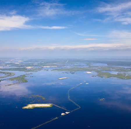 Oil field in flood field beside of great river during spring, top viewの写真素材