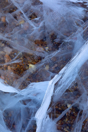 Close up shot of frozen waters with included of cracks, bubbles and herbs of baikal lake iceの写真素材