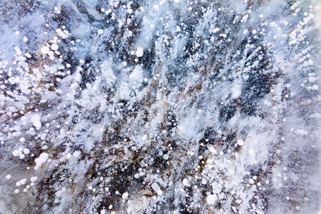 Close up shot of frozen waters with included of cracks, bubbles and herbs of baikal lake iceの写真素材