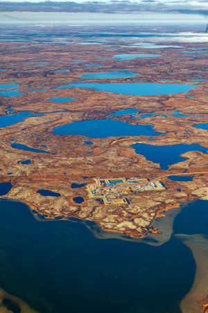 Aerial view of the tundra in autumn. Oilfield in marsh terrain under cloudy sky. Extensive gas producing province. Rig for drilling gas in Yamal region, West Siberia.の写真素材