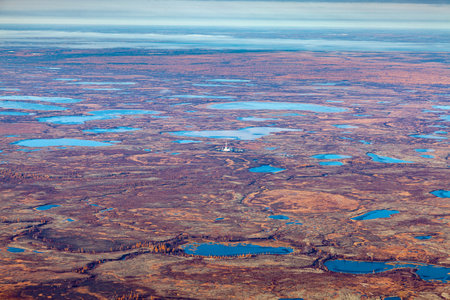 Aerial view of the tundra in autumn. Oilfield in marsh terrain under cloudy sky. Extensive gas producing province. Rig for drilling gas in Yamal region, West Siberia.の写真素材