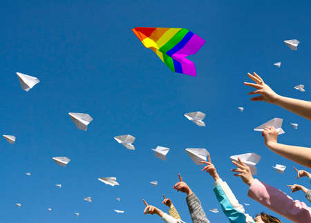 Peoples hands launch paper planes into the blue skyの写真素材