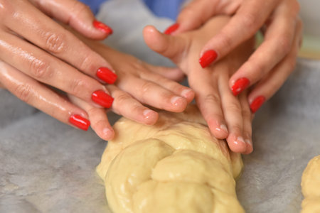 Female and kid's hands holding a piece of dough round shape closeup. Women's and kid's hands knead...