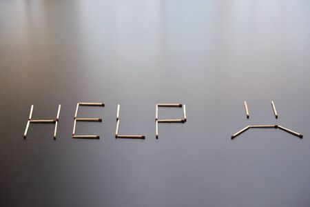 Help word with sad smile from matches. Word help with sad smile from matches on black wood. Concept of matches, the inscription Help with a sad smile.の写真素材