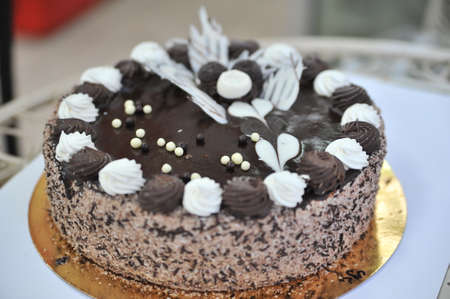 White frosted cake on the sides with hand crafted with hand crafted chocolates frosting decorations on tops.の写真素材