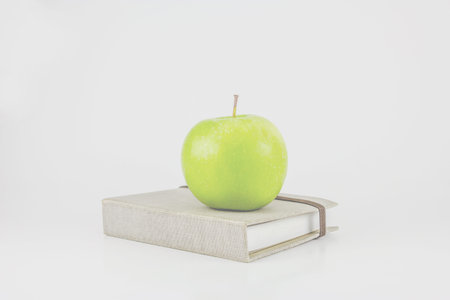 book and green apple on a white background 