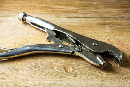 locking pliers on a wooden panel with space for textの写真素材