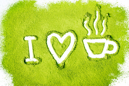 green powder forming heart and tea cup shape surface close up isolated on white background
