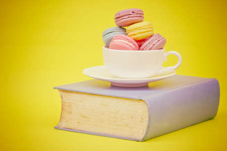 Sweet and colourful french macaroons in cup on book  retro-vintage backgroundの写真素材