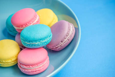colorful macaroons in plate on blue backgroundの写真素材