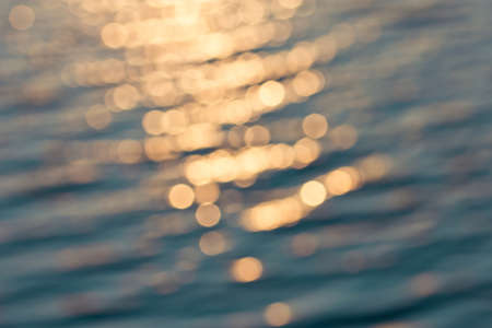Golden sunlights on blue water background の写真素材