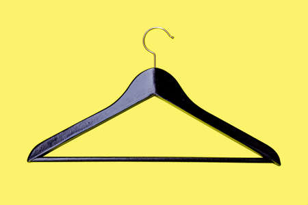 Hanger - a coat hanger for clothes, from an ebony isolated on a yellow backgroundの写真素材