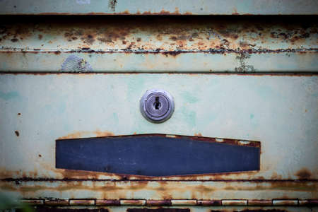 Rusty mailbox hangs off a metal fence の写真素材