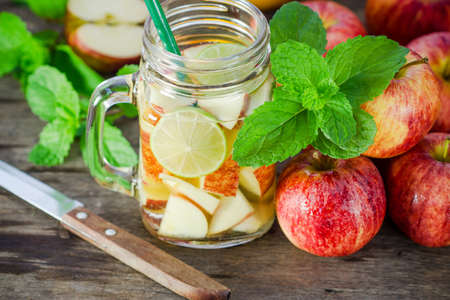 Mug delicious refreshing drink of apple fruits with mint on wooden, infused waterの写真素材