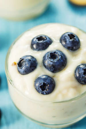 Yogurt with bilberries in glass bowls on blue tableの写真素材