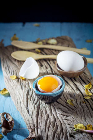Still life broken white eggs and egg yolk on a wooden rustic backgroundの写真素材