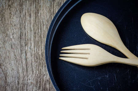 Closeup of a cast iron frying pan and wooden utensils  on wooden tableの写真素材
