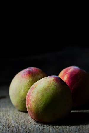 Juicy peaches in old wooden tray on black backgroundの写真素材