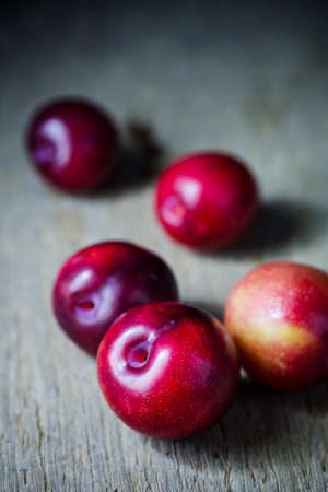 Juicy plums in old wooden tray on black backgroundの写真素材