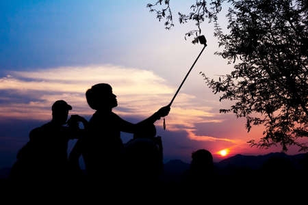 Silhouette of travelers enjoy their moment watching sunset at That Phu Si and Wat tham Phu Si, Luang Prabang Laos.の写真素材