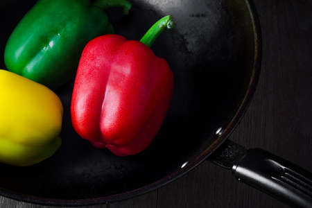 Peppers and lemon on dark frying panの写真素材