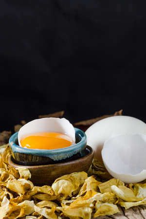 broken chicken eggs and egg yolk on black background.の写真素材