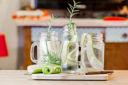 glass jars of cucumber and rosemary on wooden tableの写真素材