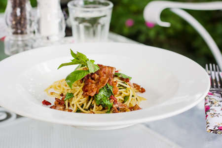 Spaghetti bacon chili with dried tomatoes and basil leafの写真素材