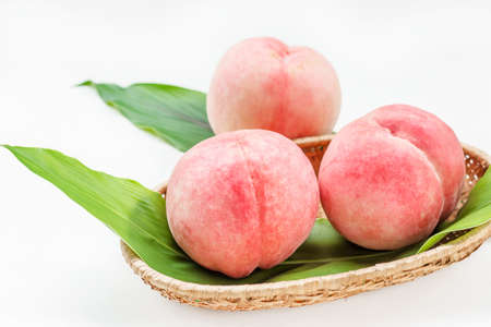 Peaches in basket on white wooden backgroundの写真素材