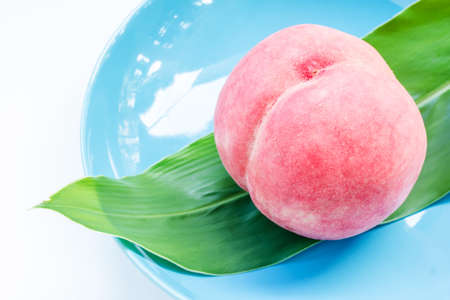 Ripe peach in ceramic plate on wooden backgroundの写真素材