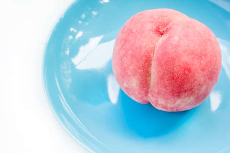 Ripe peach in ceramic plate on wooden backgroundの写真素材