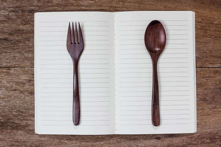 recipe book and spoon,fork on wooden table.の写真素材