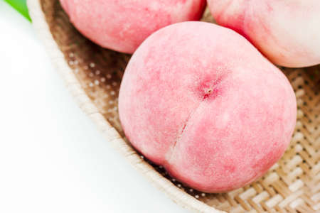 Peaches in basket on white wooden backgroundの写真素材