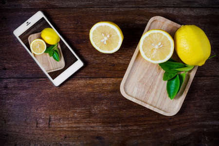 Fresh slice lemons with leaves on wooden background.の写真素材